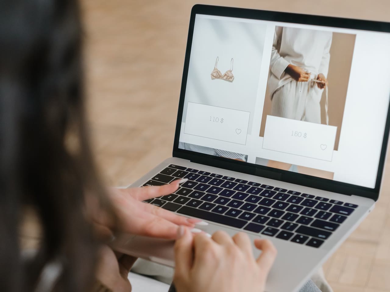 Mulher consulta uma loja de roupas no notebook, com as mãos sobre o teclado